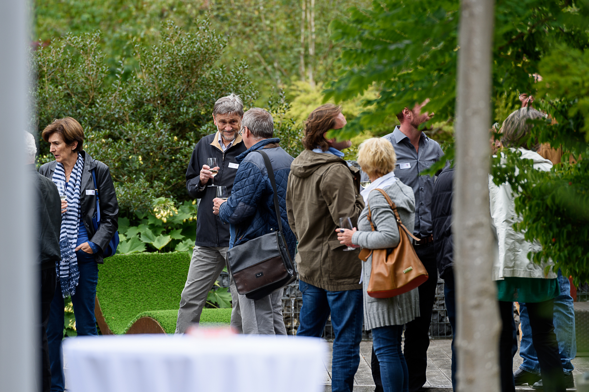 Menschen in einer Gartenumgebung bei einer Veranstaltung Gruppe von Menschen, die in einer Gartenumgebung bei einer Veranstaltung miteinander sprechen.