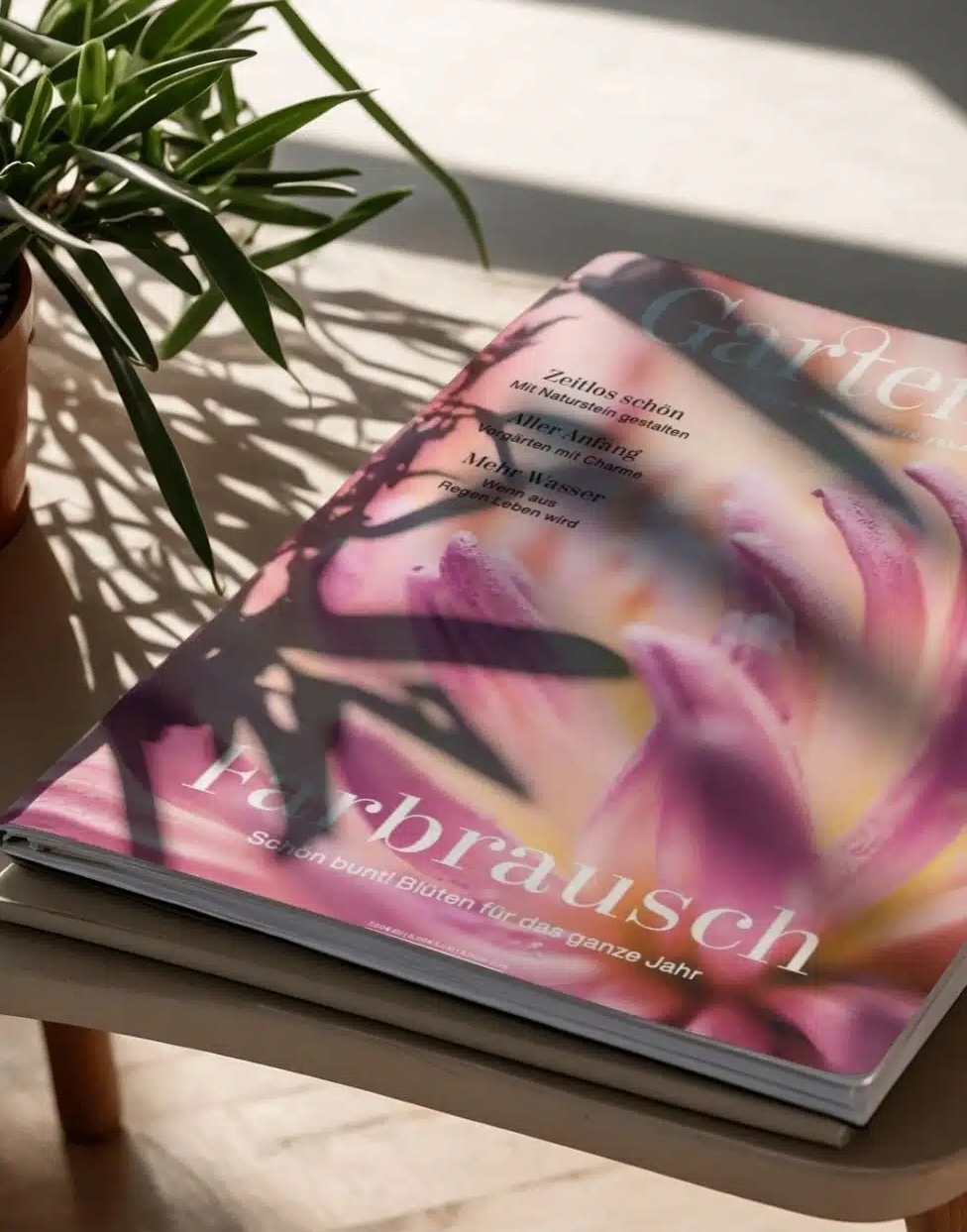 Teaserbild_GatrenArt_980x1251 Cover des Magazins GartenArt mit einer Hand und Pflanzenmotiven auf rosa Hintergrund.